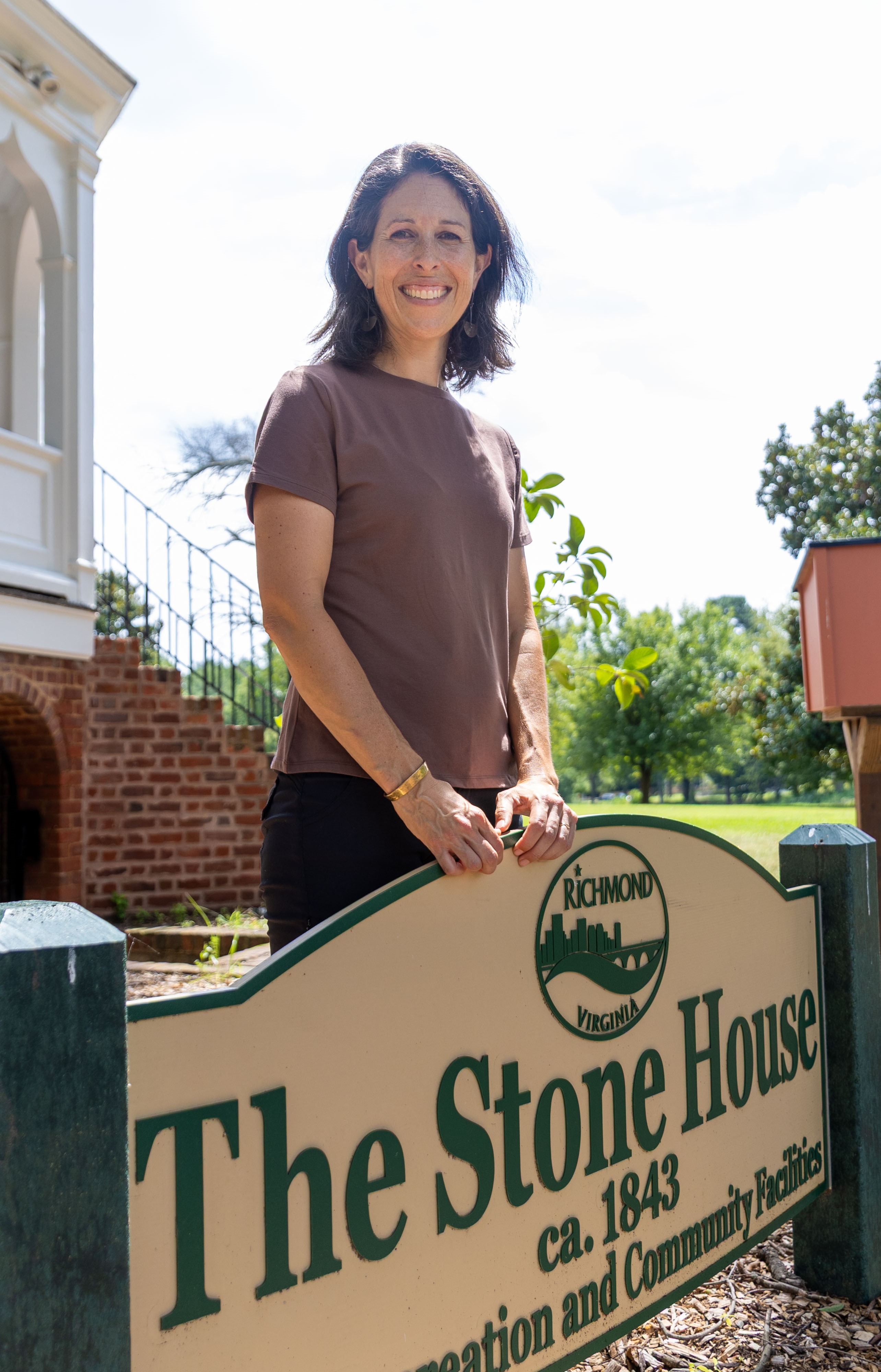 Giles Garrison poses behind the Stone House sign at Forest Hill Park.